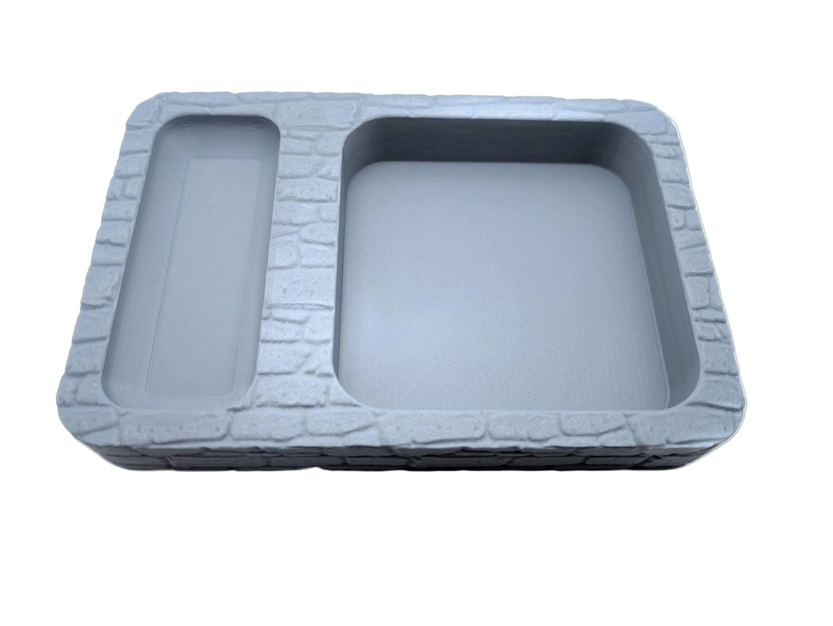 A grey dice tray with two compartments for storing and rolling dice during role play table top games, stone texture